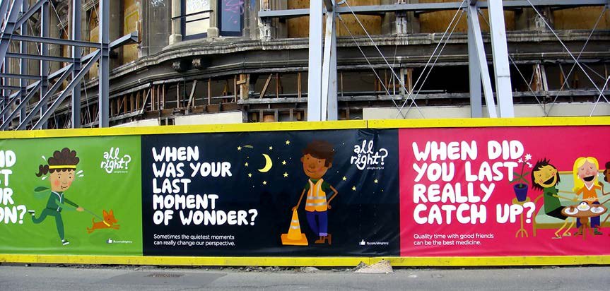 A long construction hoarding in Christchurch carrying the All Right? campaign, with brightly illustrated panels asking questions such as when was your last moment of wonder.